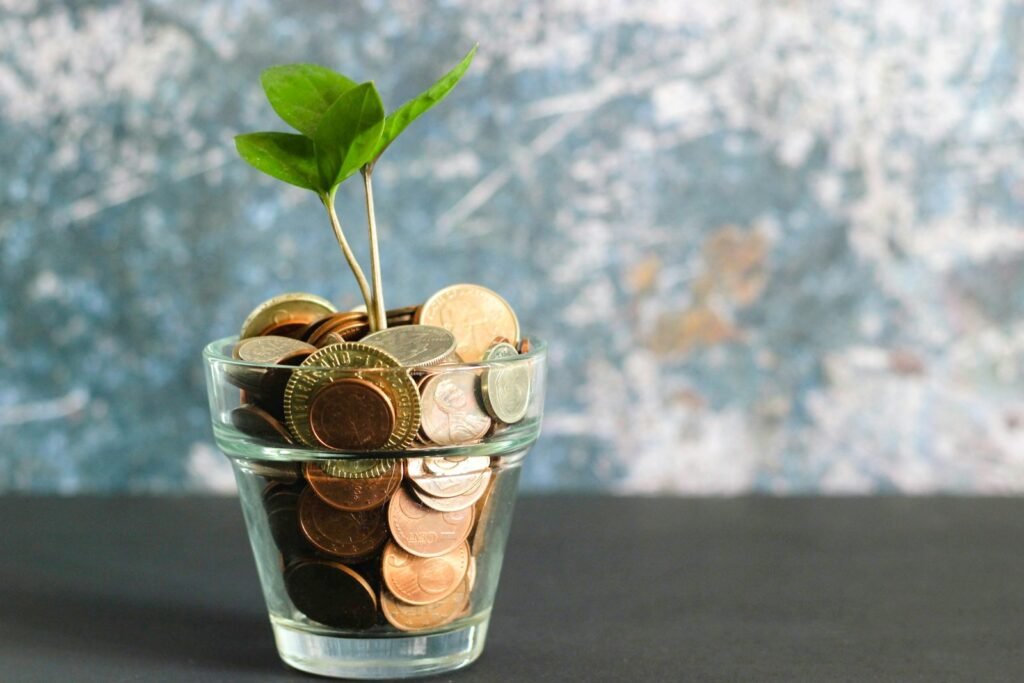 Glass of coins with a green plant sprout growing from it